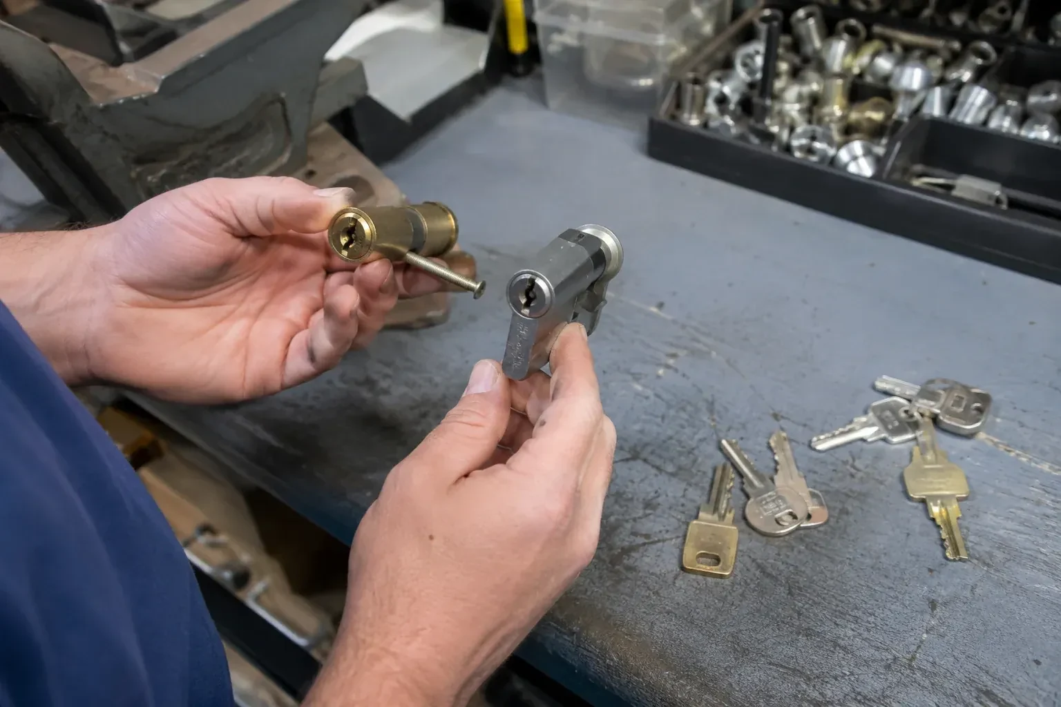 Hands comparing detached lock cylinders beside loose keys on a workbench. — Broken Key Extraction, Kawartha Lakes
