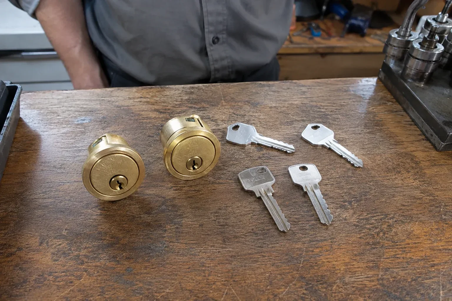 Two detached brass lock cylinders and four house keys on a wooden counter. — Lock Rekeying, Kawartha Lakes